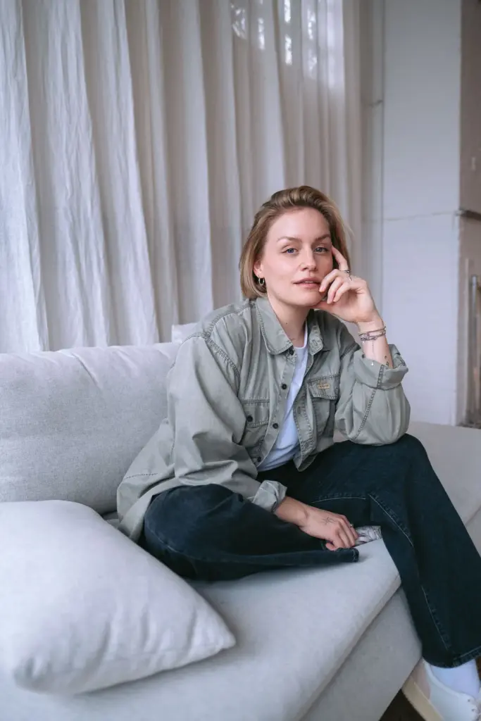 Maischa Pingel sitzt lässig auf einer beigen Couch. Maischa Pingel ist Influencerin, Content Creatorin & Podcasterin.